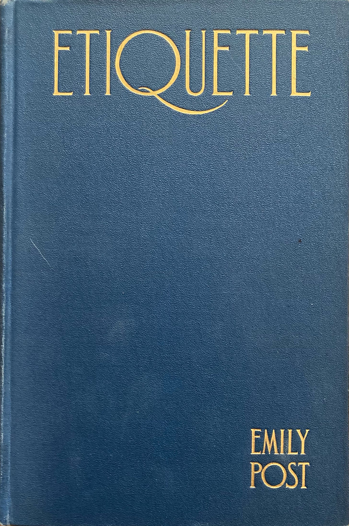 EMily Post's Etiquette from 1922 A dark blue leather book with gold debossed art decco lettering that reads ETIQUETTE across the top and in the lower right neatly stacked is the author's name Emily Post