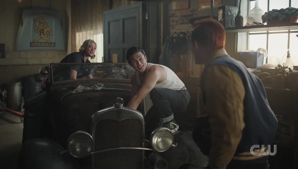Betty and Reggie work on a classic car while Archie watches