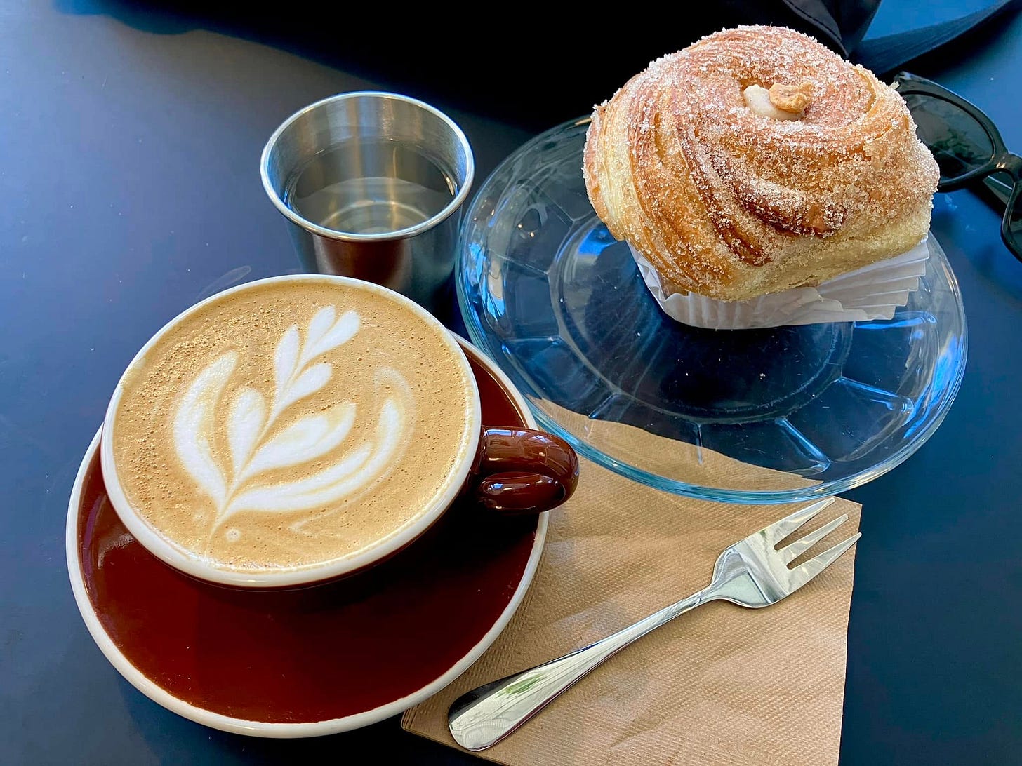 May be an image of coffee cup, coffee and cinnamon roll