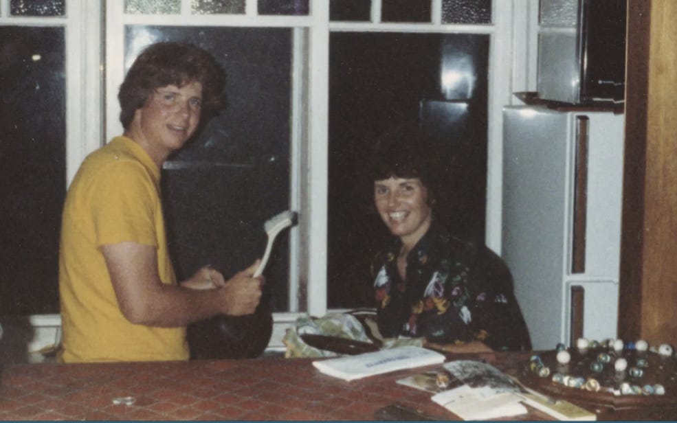 A chunky looking Michael on the left in a yellow shirt, Shan on the right drying dishes. 