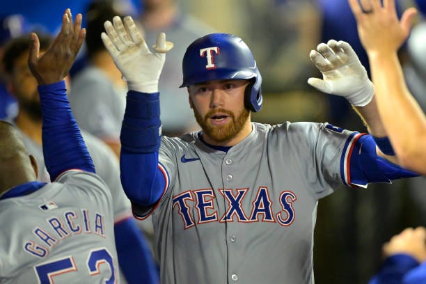 Carson Kelly of the Texas Rangers is congratulated in the dugout after hitting a solo home run in the fourth inning against the Los Angeles Angels at...