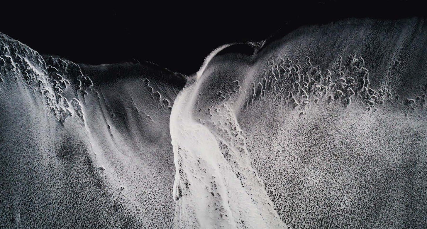 Greyscale overhead aerial image of surf at a beach