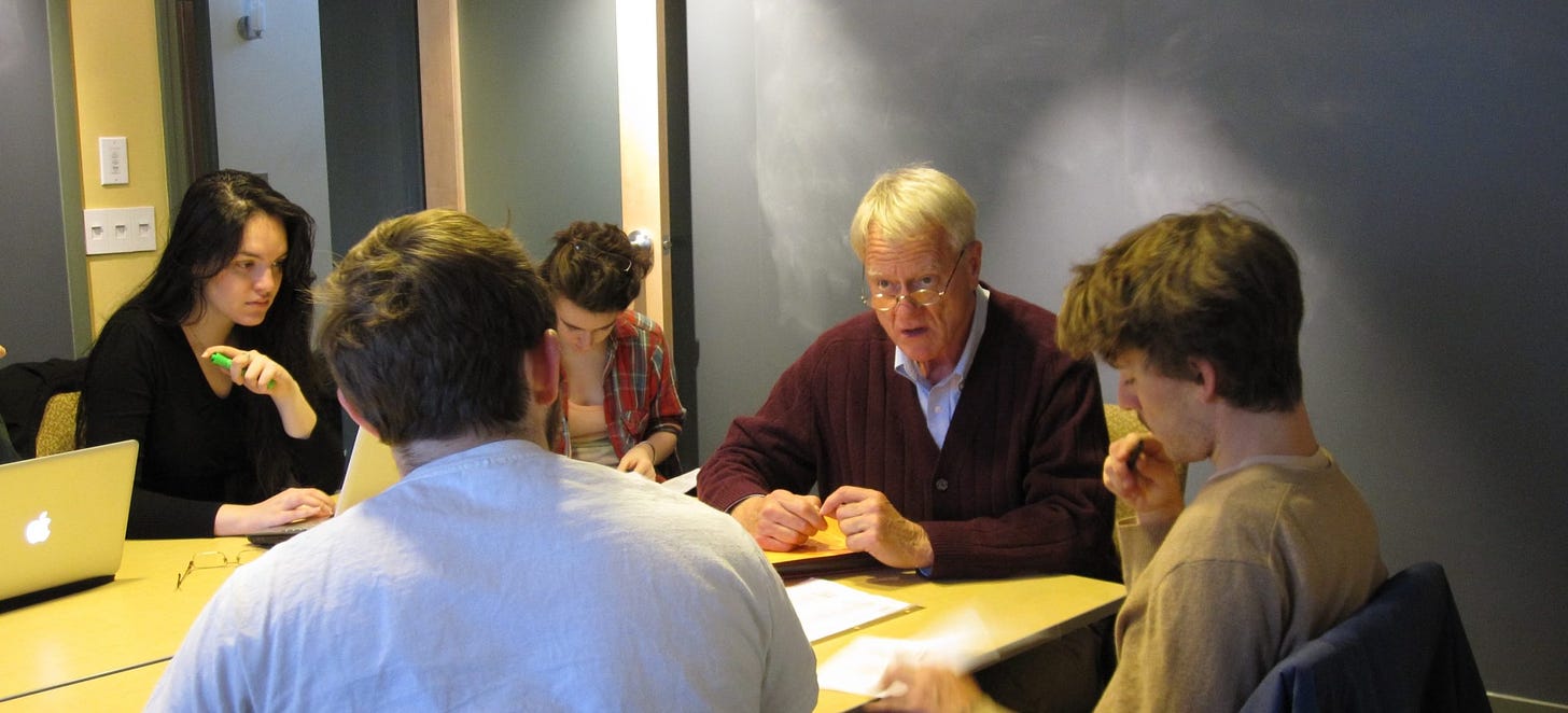 Students and Lakey sitting around a table looking at papers and computers.