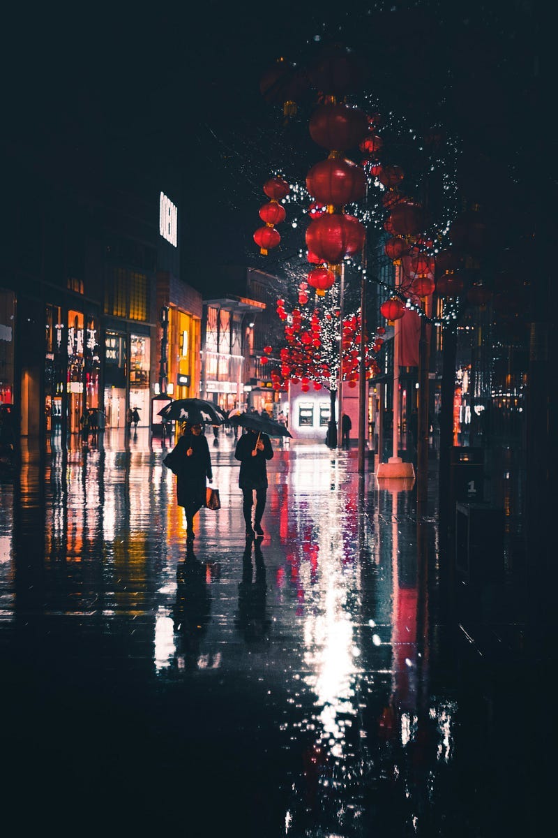 A rainy and dark night with two people walking with umbrellas. A rainy and dark night with two people walking with umbrellas.