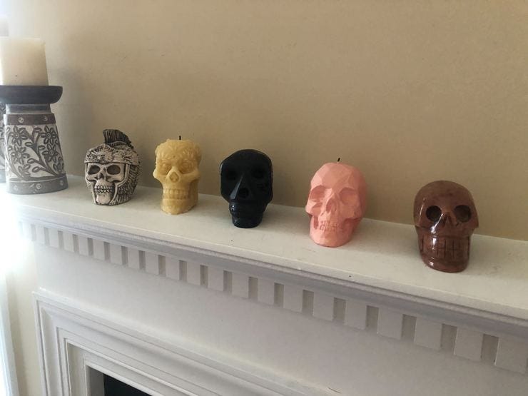 Several wax and stone skulls on a mantle