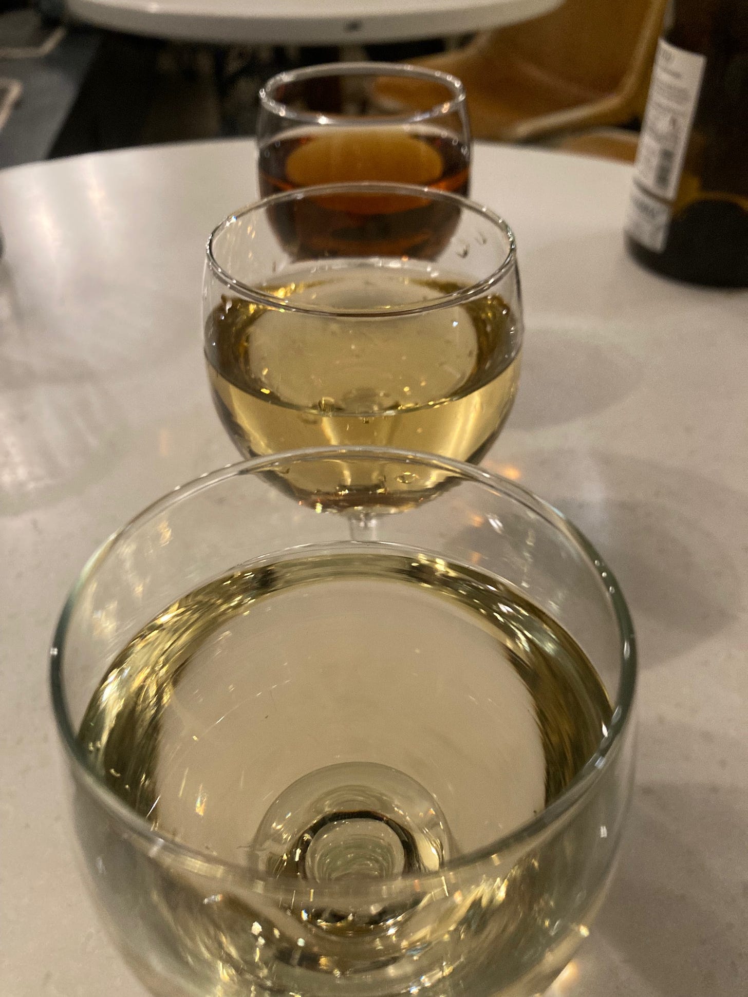 Three glasses of sherry, all different in colour, stand one behind each other on a table.