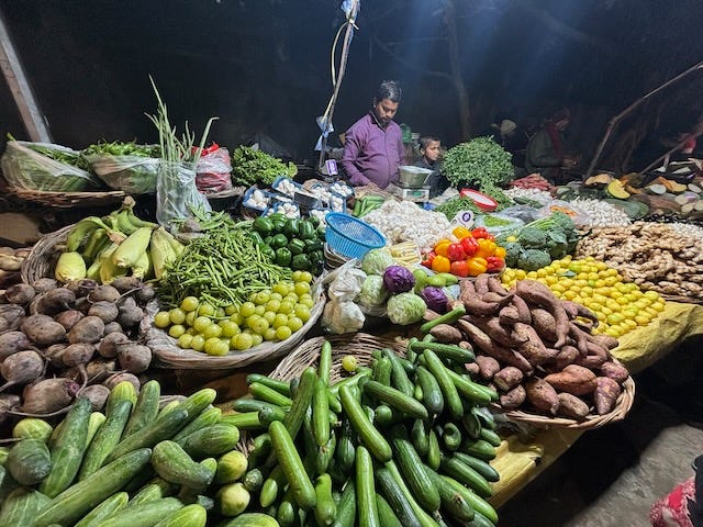 A vegetable seller with many vegetables at a night market in Noida, India