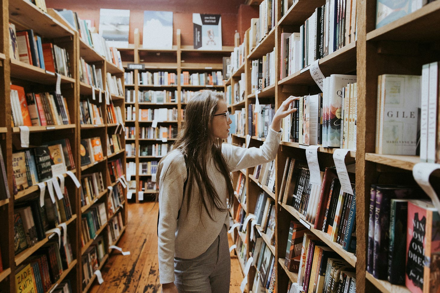 teen girl with long hair and glasses, browsing in a bookstore