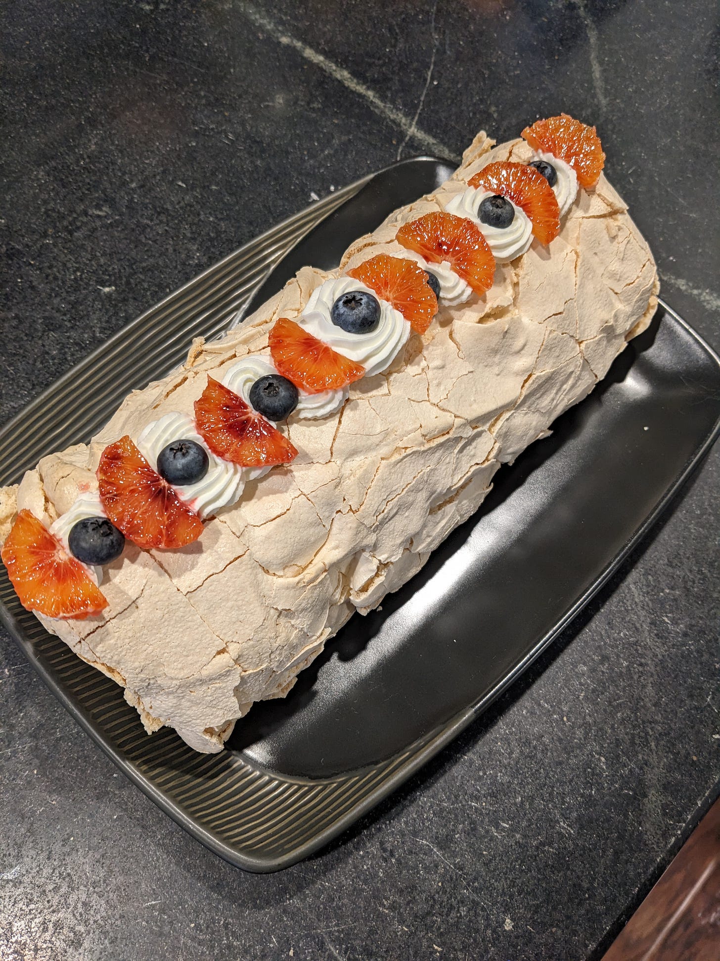 A meringue roulade on a black plate