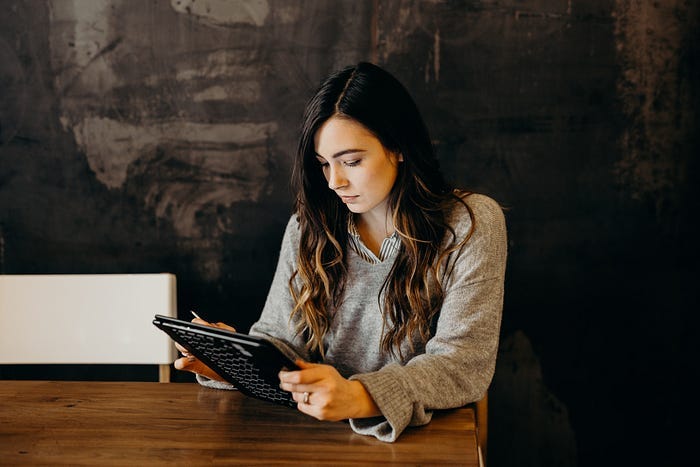 A woman sadly looking at a tablet. A woman sadly looking at a tablet.