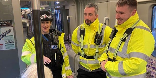 An Essex Police officer and two transport safety officers talk to a train passenger