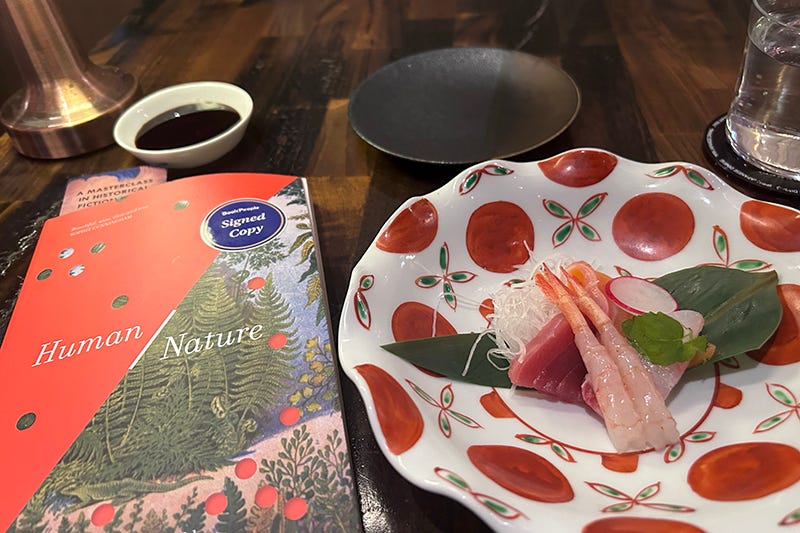 A copy of ‘Human/Nature’ by Jane Rawson next to a plate of sashimi.