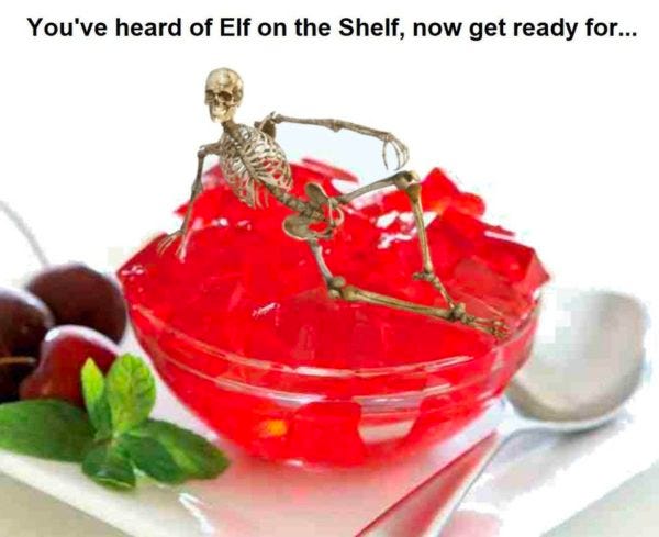 Caption: You’ve heard of Elf on the Shelf, now get ready for …  Photo of a bowl of jello with a spoon and a few cherries. On top of the jello is a small skelton. A skeleton on gelatin.
