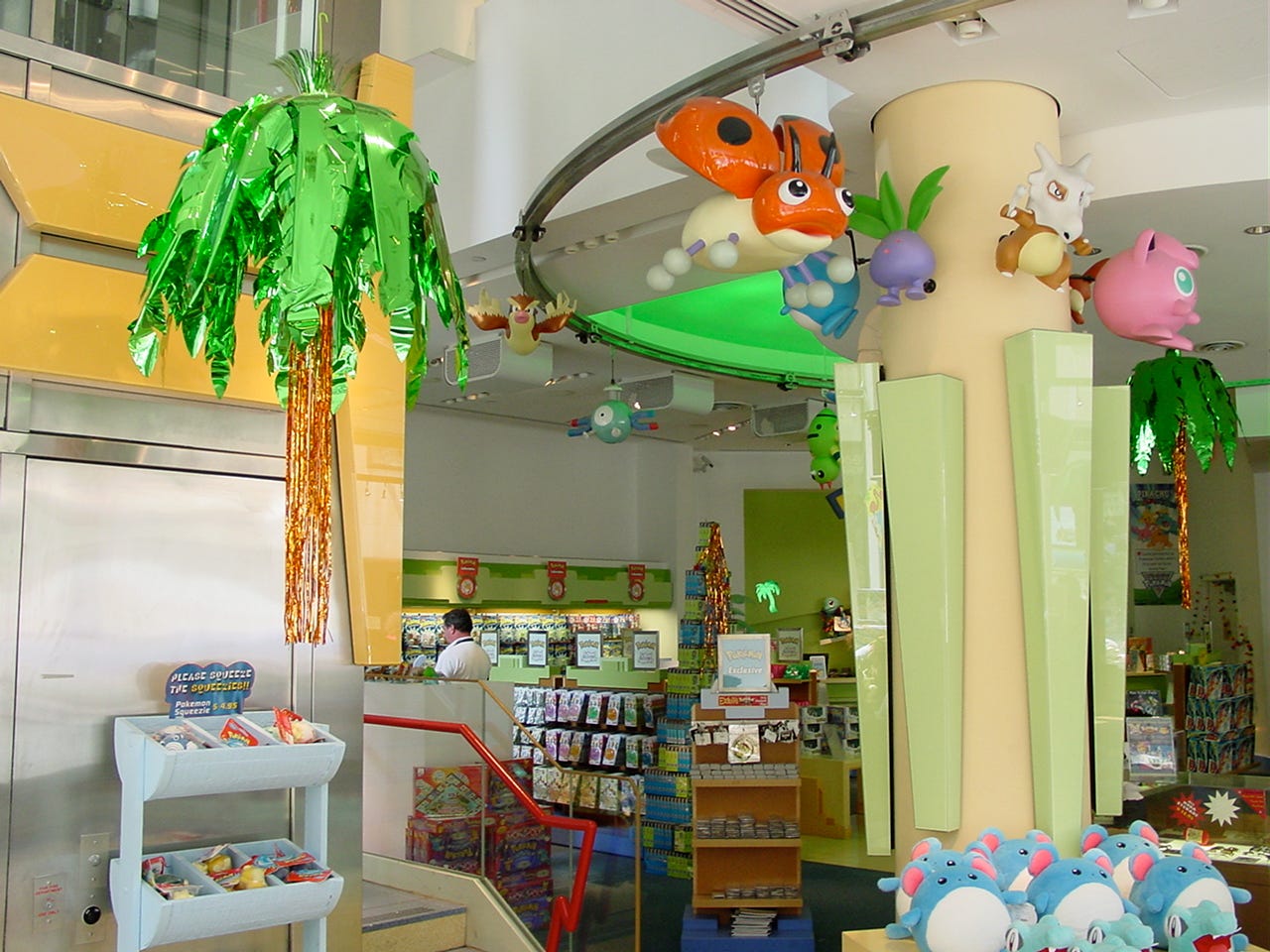 Another photograph of the lower floor, showing the statues and more merchandise. The store’s elevator can also be seen here, allowing visitors to reach areas such as the dedicated gaming area and the Pokémon Distribution Machine on the second floor