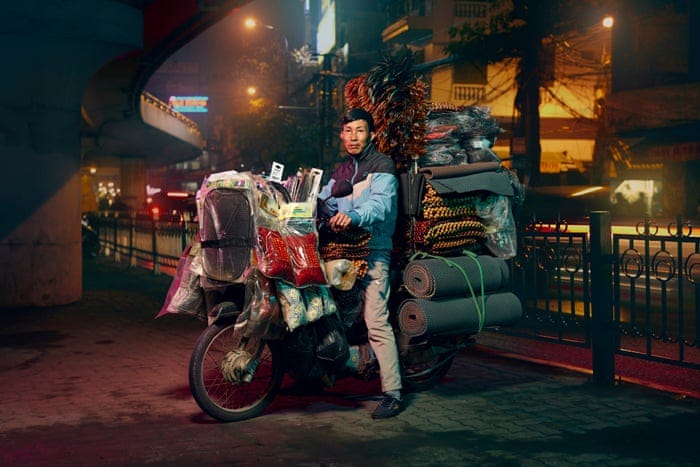 Delivery driver in hanoi - on a moped with many items at the back and the front of the moped