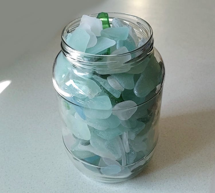A jar full of fragments of pale blue and green sea glass