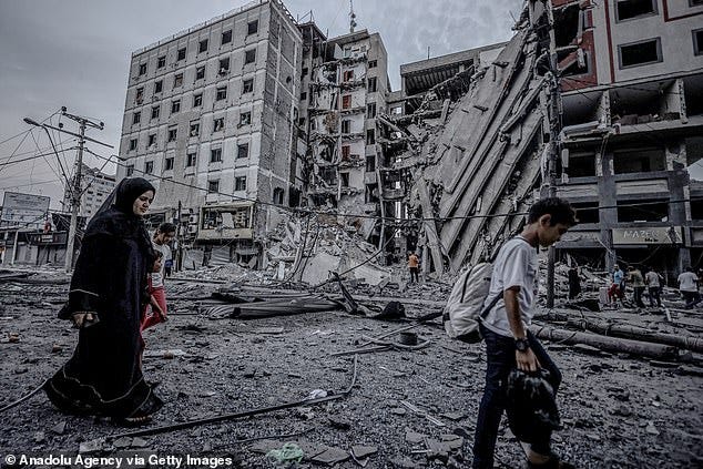 People are pictured walking through the Rimal district of Gaza City on Sunday after airstrikes on Islamic National Bank of Gaza destroyed buildings and neighbourhoods