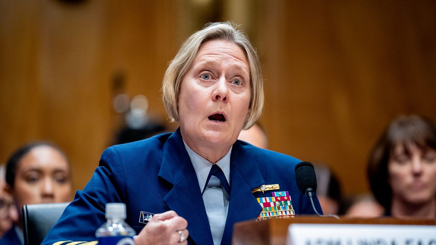 Linda Fagan, in uniform, sits at a desk and speaks into a microphone. 