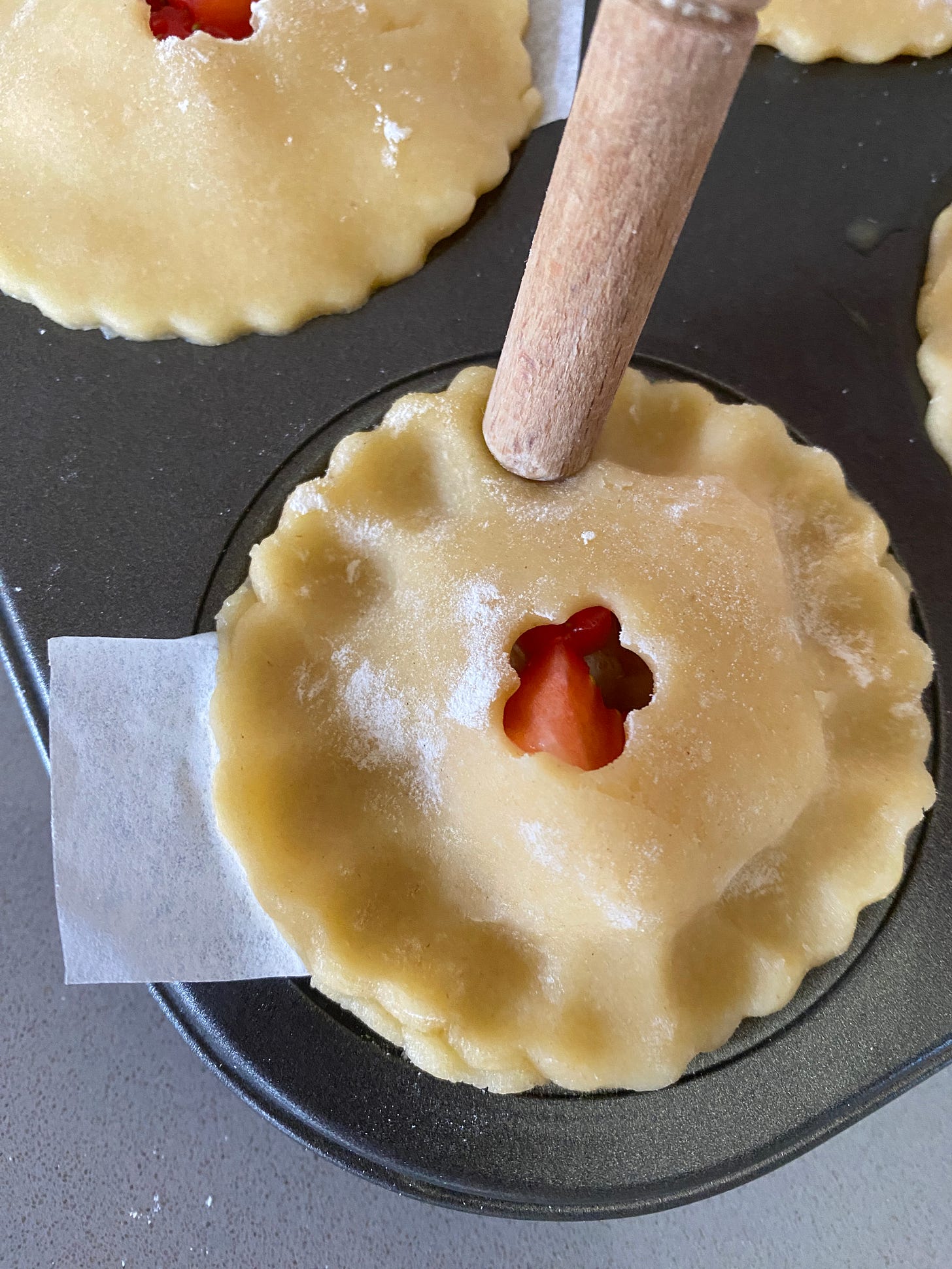 six unbaked fruit pies in a baking tin.