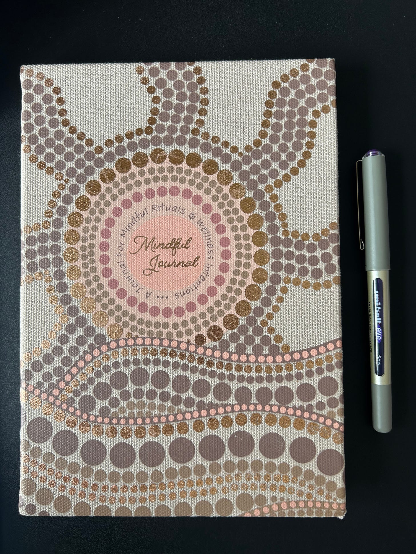 The front of a journal that has an Aboriginal dot painting design.