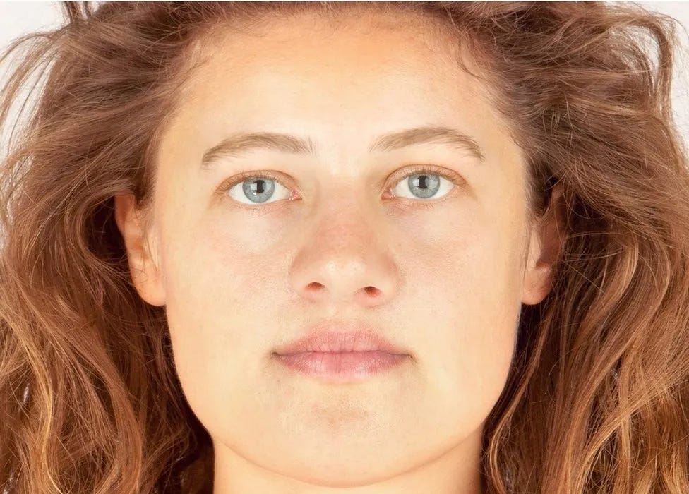 A lifelike representation of a young white woman with golden brown hair and pale blue eyes. Her forehead and jaw are very wide
