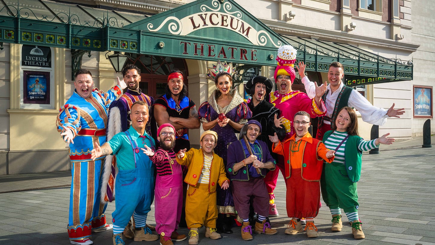 The cast assembled in brightly coloured costumes outside the Lyceum Theatre with the dwarfs in the front row.