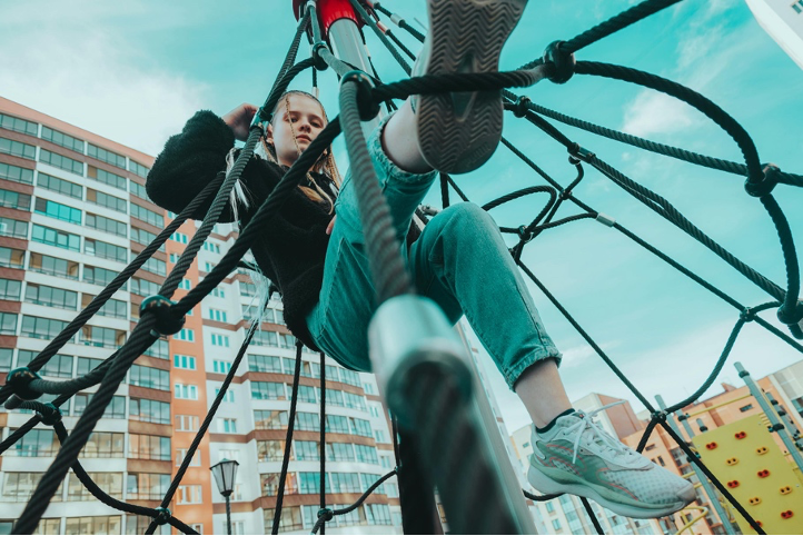 Teen girl climbing on playground equipment