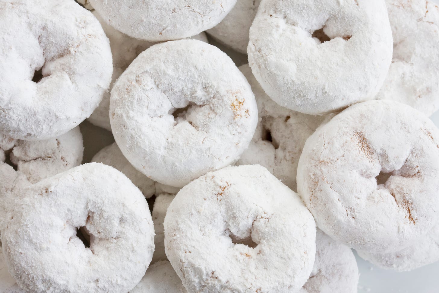 an overhead picture of many powdered sugar donuts stacked on top of each other