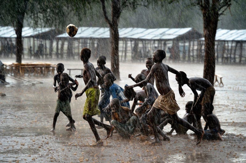 Children play football during an October 2012 rainstorm in the Doro refugee camp in South Sudan's Upper Nile State. More than 110,000 refugees had come to camps in Maban County from Sudan's Blue Nile region, where the Sudanese military was bombing civilian populations as part of its response to a local insurgency. Under "informed consent" rules that require prior approval, the photographer would have had to stop the boys from playing, have them find and identify their parents somewhere in the sprawling camp, explain the intricacies of "informed consent" and usage, get their signatures, and then return to photograph the game. That's a process that's allegedly designed to assure that the boys are not depicted in an undignified manner. Photo by Paul Jeffrey. Children play football during an October 2012 rainstorm in the Doro refugee camp in South Sudan's Upper Nile State. More than 110,000 refugees had come to camps in Maban County from Sudan's Blue Nile region, where the Sudanese military was bombing civilian populations as part of its response to a local insurgency. Under "informed consent" rules that require prior approval, the photographer would have had to stop the boys from playing, have them find and identify their parents somewhere in the sprawling camp, explain the intricacies of "informed consent" and usage, get their signatures, and then return to photograph the game. That's a process that's allegedly designed to assure that the boys are not depicted in an undignified manner. Photo by Paul Jeffrey.