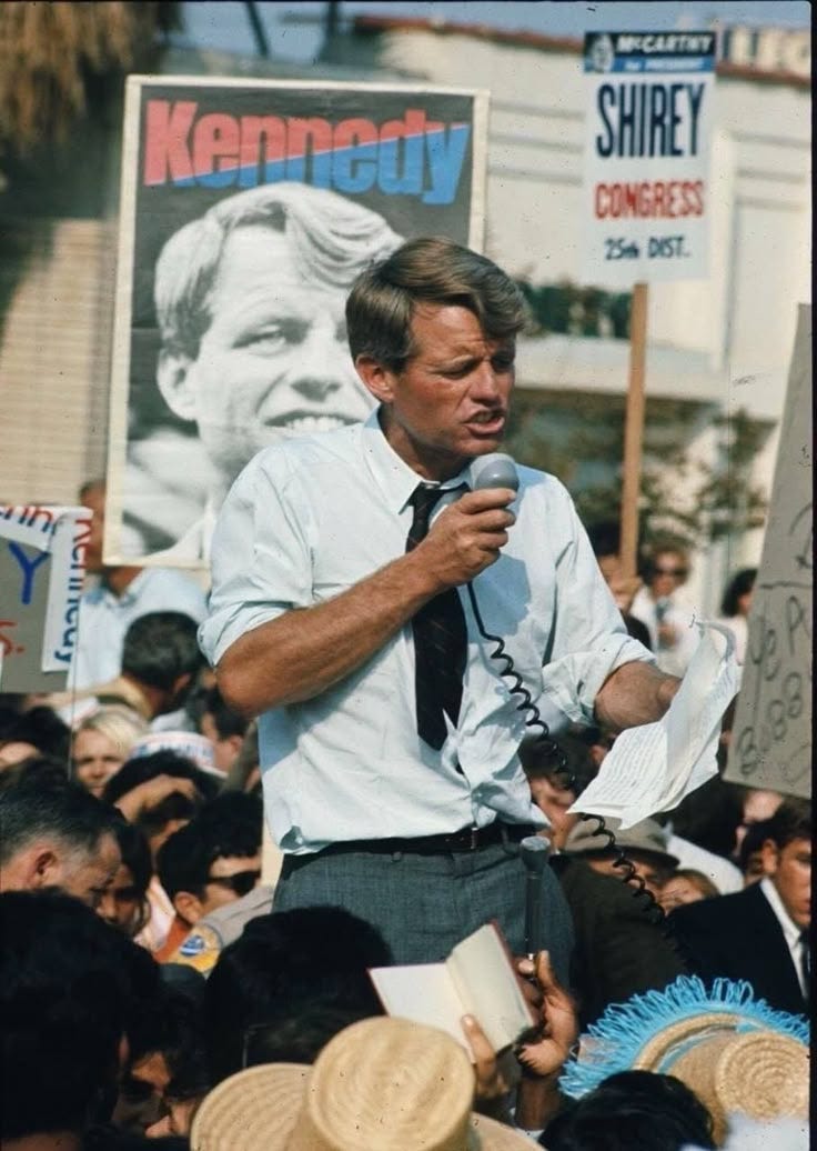 This may contain: a man standing in front of a crowd holding a microphone