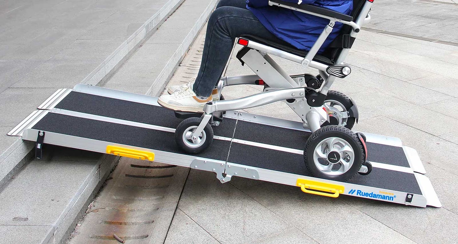 Wheelchair user rolling up a portable ramp.