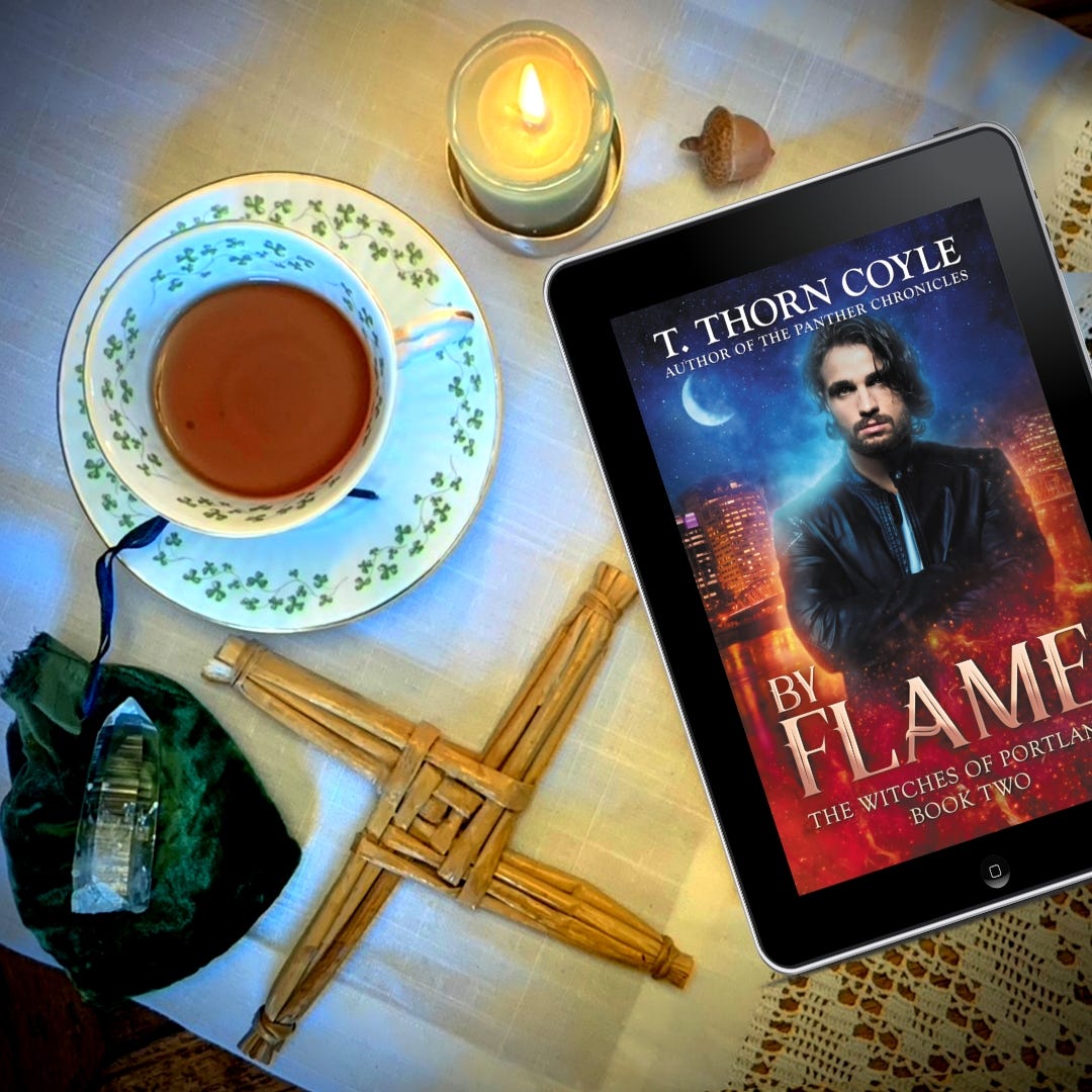 Shamrock teacup, woven Brigid's cross, a candle, a crystal, and an reader with By Flame book. A white man with dark hair and leather jacket in front of a glowing city skyline.