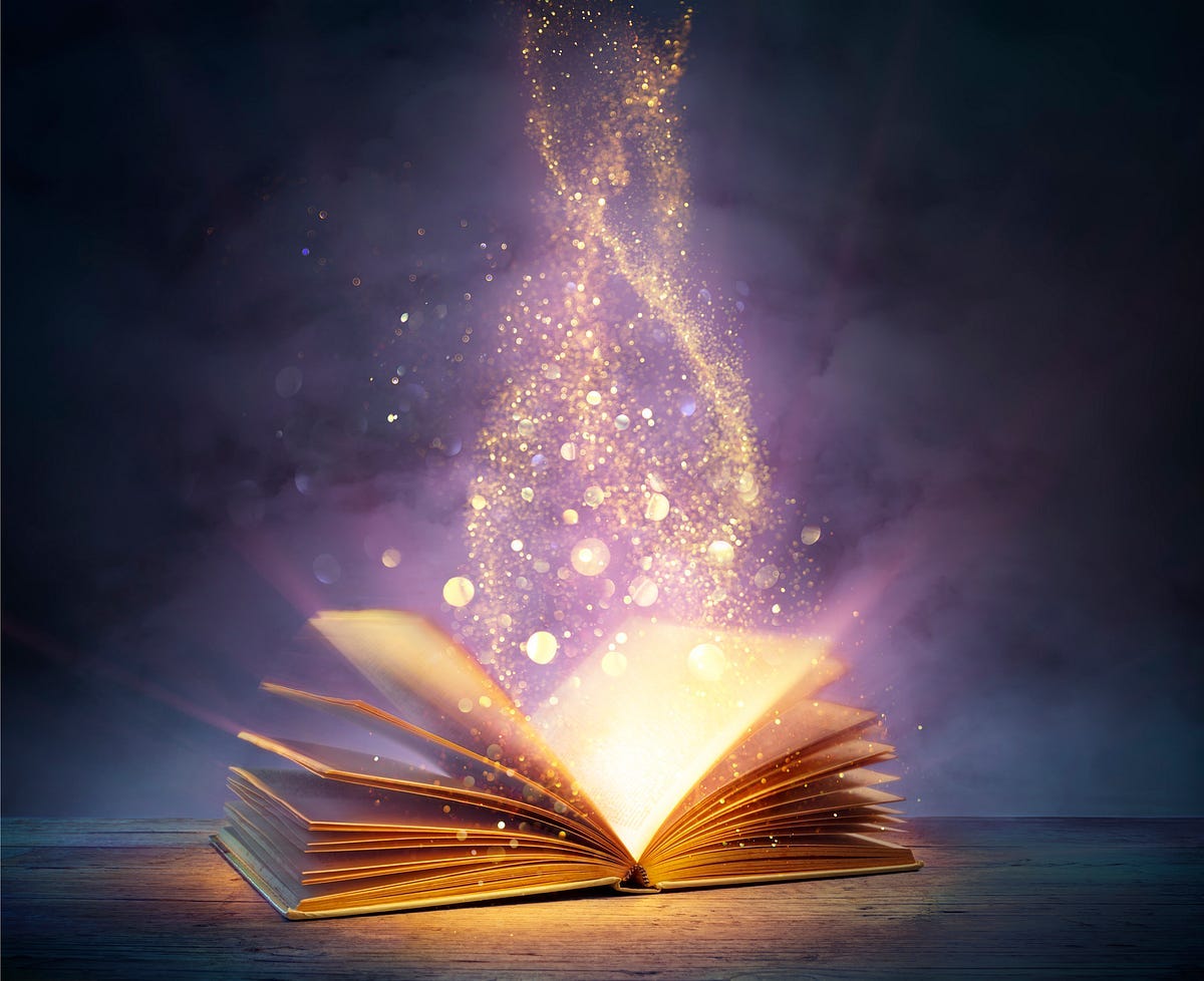 Open book with gold light and “fairy dust” rising above it as if to indicate magic.