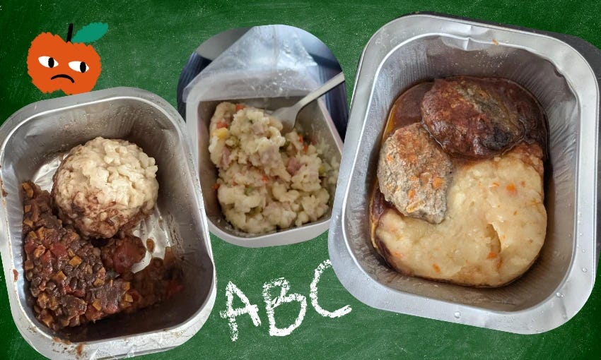 Three unidentifiable lunches in tin trays sit on top of a school blackboard with ABC written in chalk