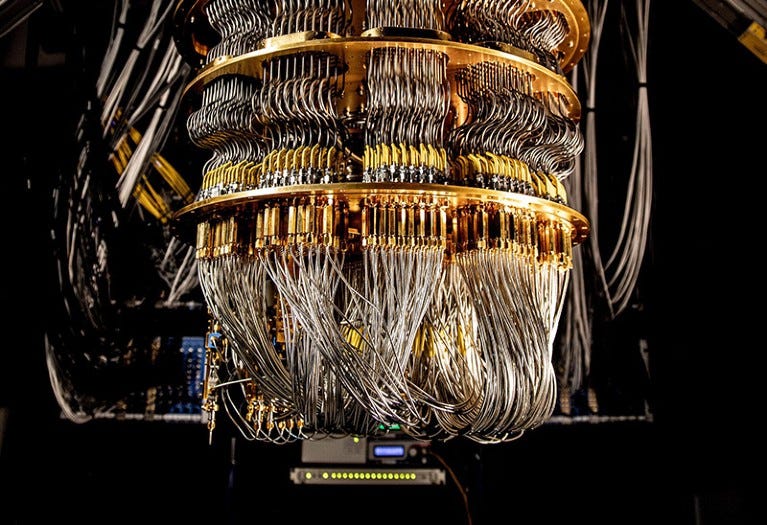 The base of Google Quantum AI computer showing shiny silver wires and gold connectors linking the bottom to top of device
