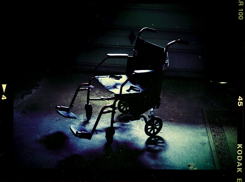 An empty vintage wheelchair abandoned at the bottom of a dark stairwell. An empty vintage wheelchair abandoned at the bottom of a dark stairwell.
