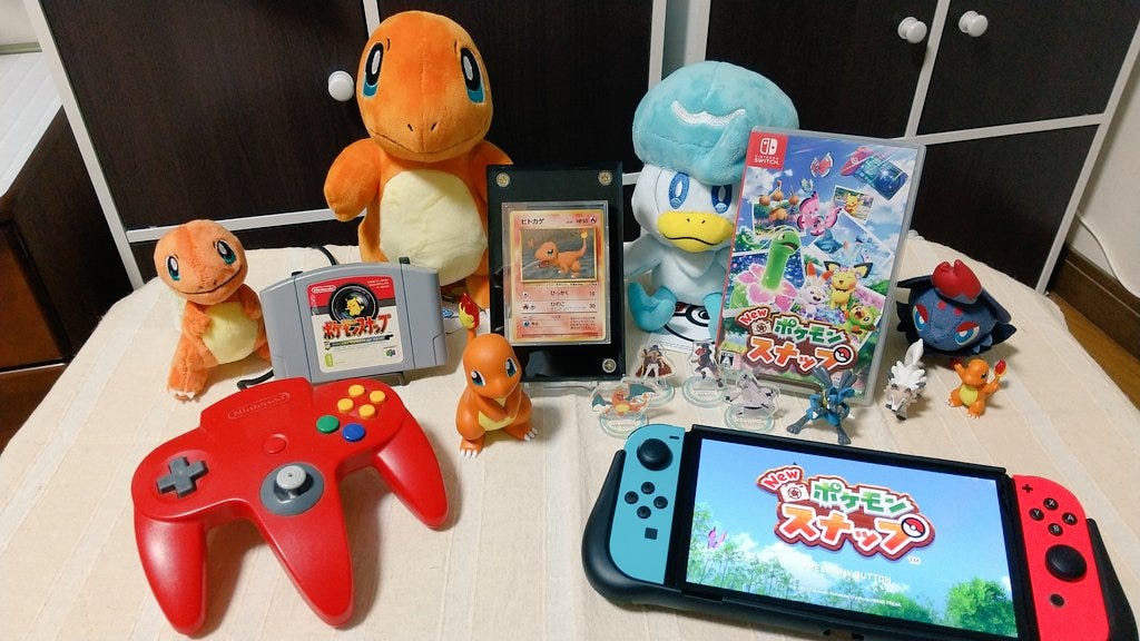 Tsukasa's collection of Pokémon figures, alongside copies of Pokémon Snap and New Pokémon Snap, and Charmander card