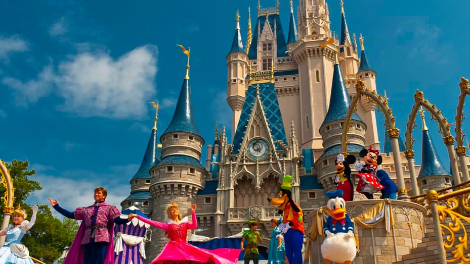 Image of Cinderella's Castle at Disney with prince and princesses dancing in front among characters.