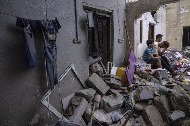 Palestinians sit on the rubble of a house after it was struck by an Israeli airstrike in Khan Younis