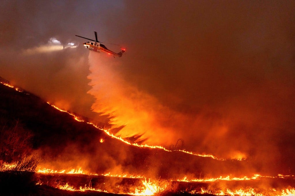 A helicopter drops water on the Kenneth Fire in the West Hills of Los Angeles on Jan. 9, 2025.