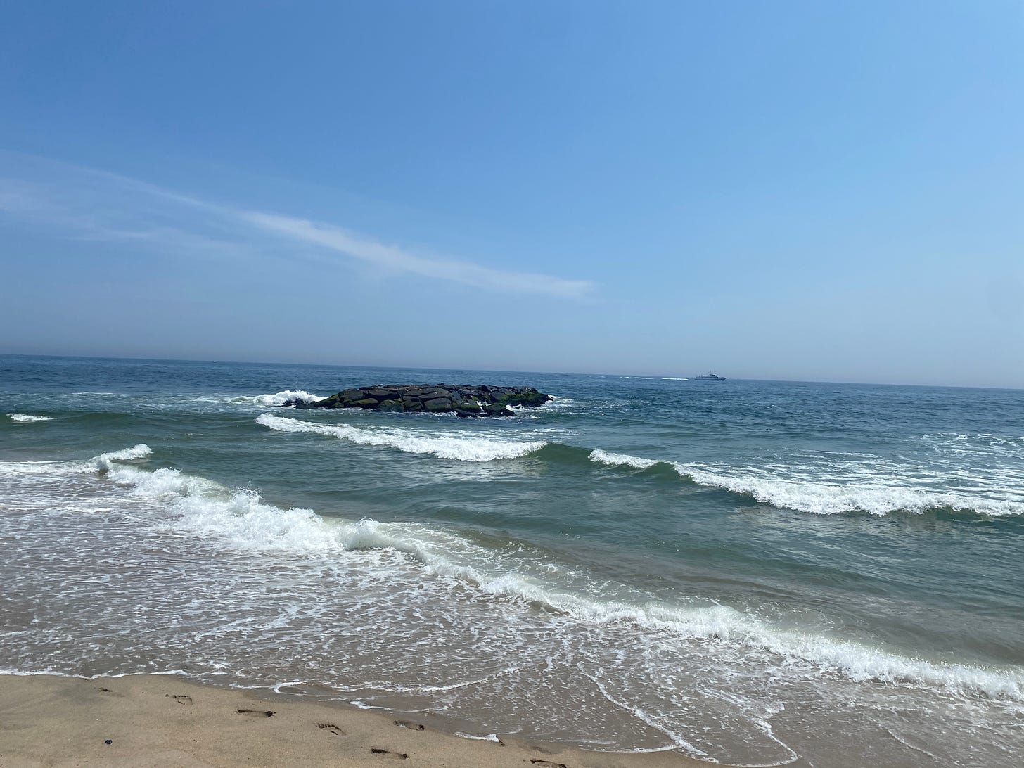 waves across the ocean, a patch of large rocks just into the sea