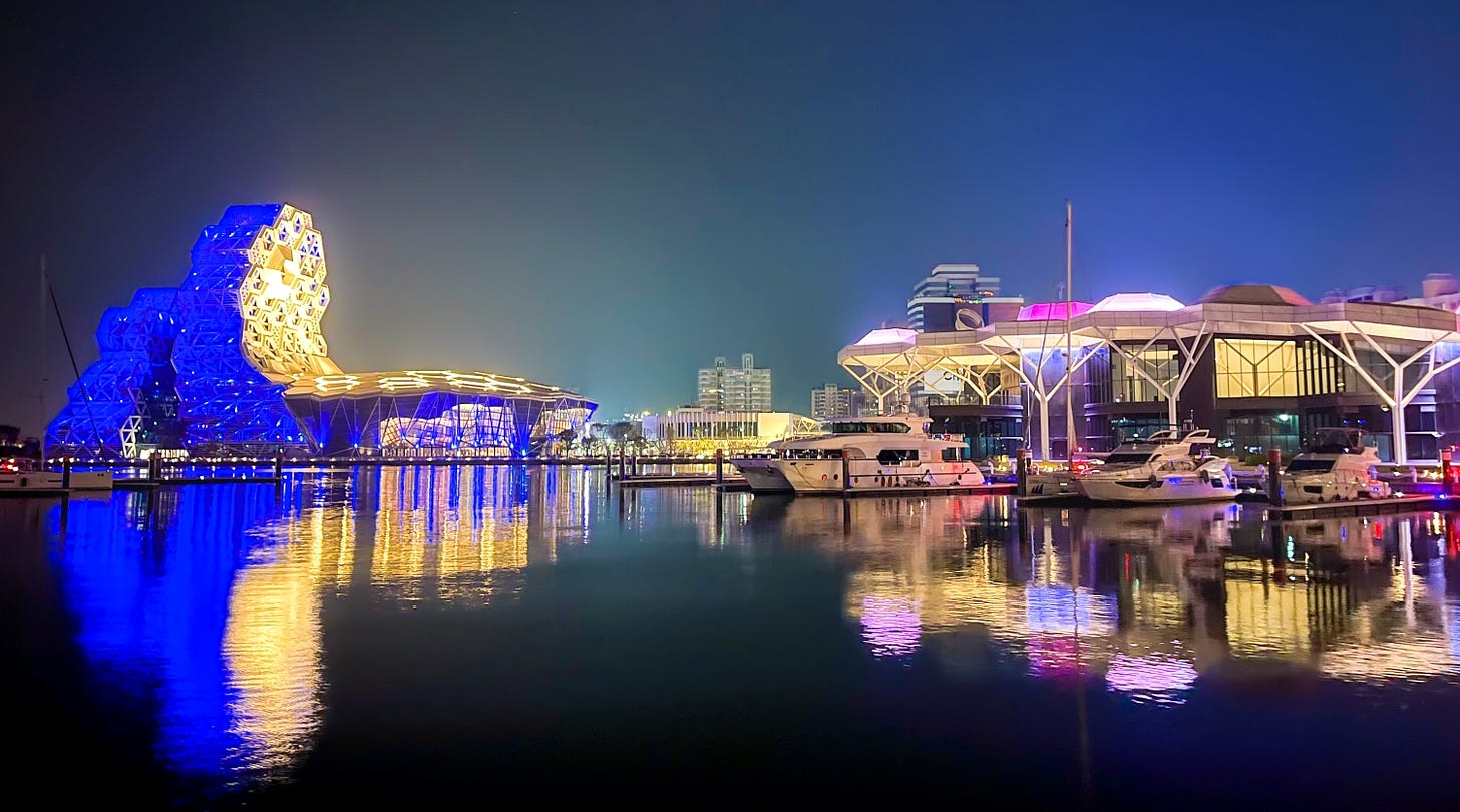 The lights of the Kaohsiung Music Center and the Kaohsiung Yacht Club are reflected in the waters of the city’s marina