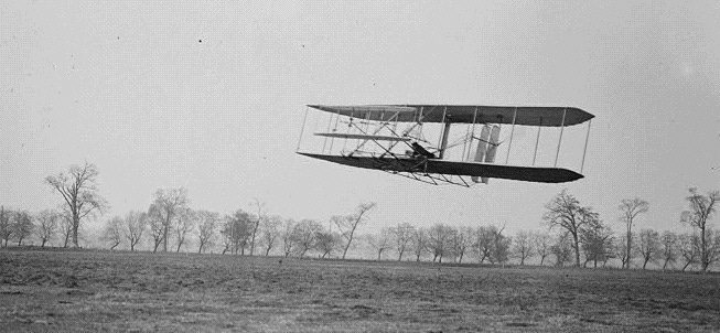 A wright flyer is pictured in the air.