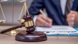 A man in a suit sitting with a gavel