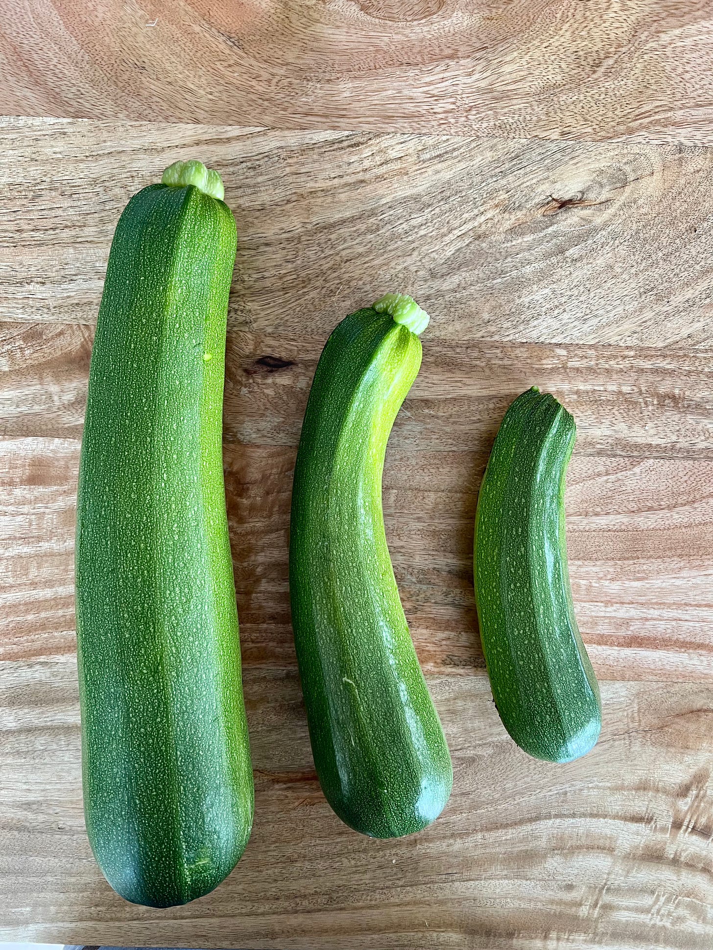 Photo of 3 zucchini on a wood table.