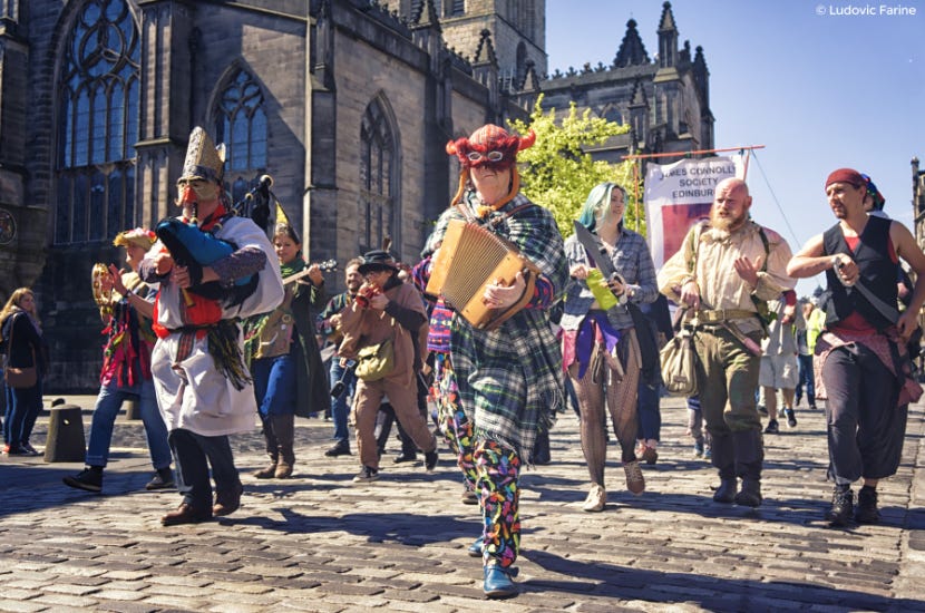 Group of people dressed as mummers and playing traditional instruments, parading down the Royal Mile in Edinburgh.