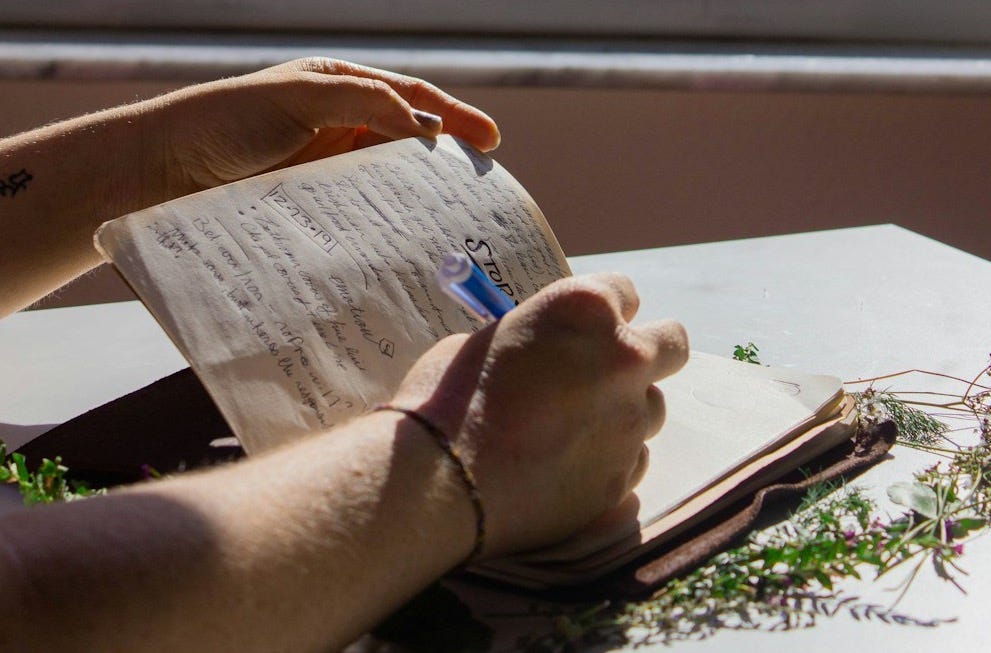 a person sitting at a table writing on a piece of paper