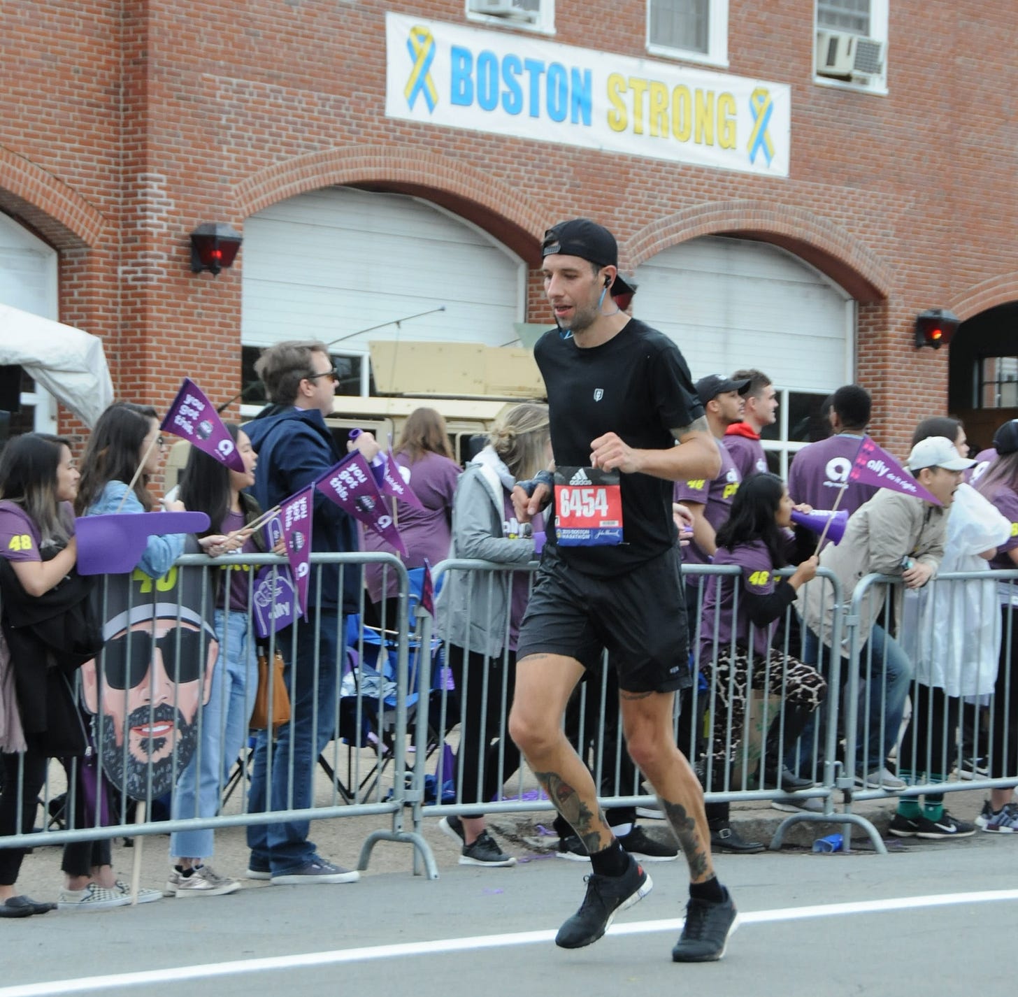 The author racing Boston Marathon suffering in front of a "Boston Strong" banner
