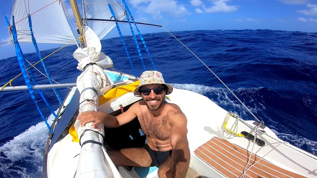 Nicholas in the cockpit of his boat. Blue Atlantic Ocean behind