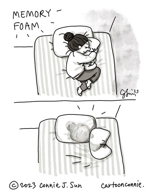 Memory Foam Pillows 2-panel autobio comic of a cartoon girl with a bun, sleeping on memory foam pillows. Panel 1: Overhead view of the girl, laying on her side, with her head on one pillow and hugging another pillow, like it's a teddy bear. Panel 2: Overhead view of the bed, with just the pillows, one with the indentation of her profile, the other misshapen from being squeezed. Cartoon illustration by Connie Sun, cartoonconnie, 2023.